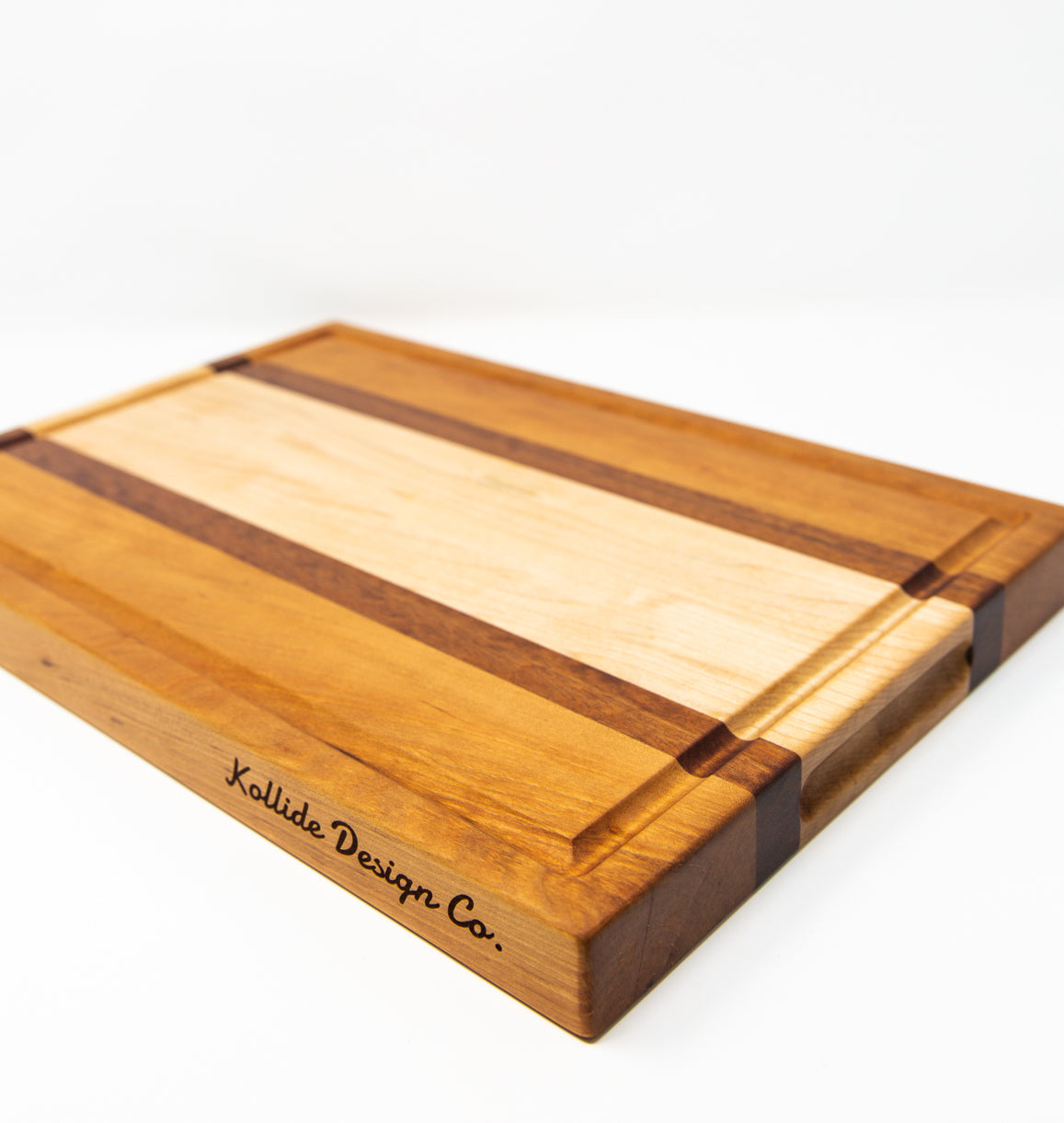 Large size wood cutting board, made of golden-brown Cherry, dark reddish-brown Sapele and light blonde Maple, with a juice groove and side handles.