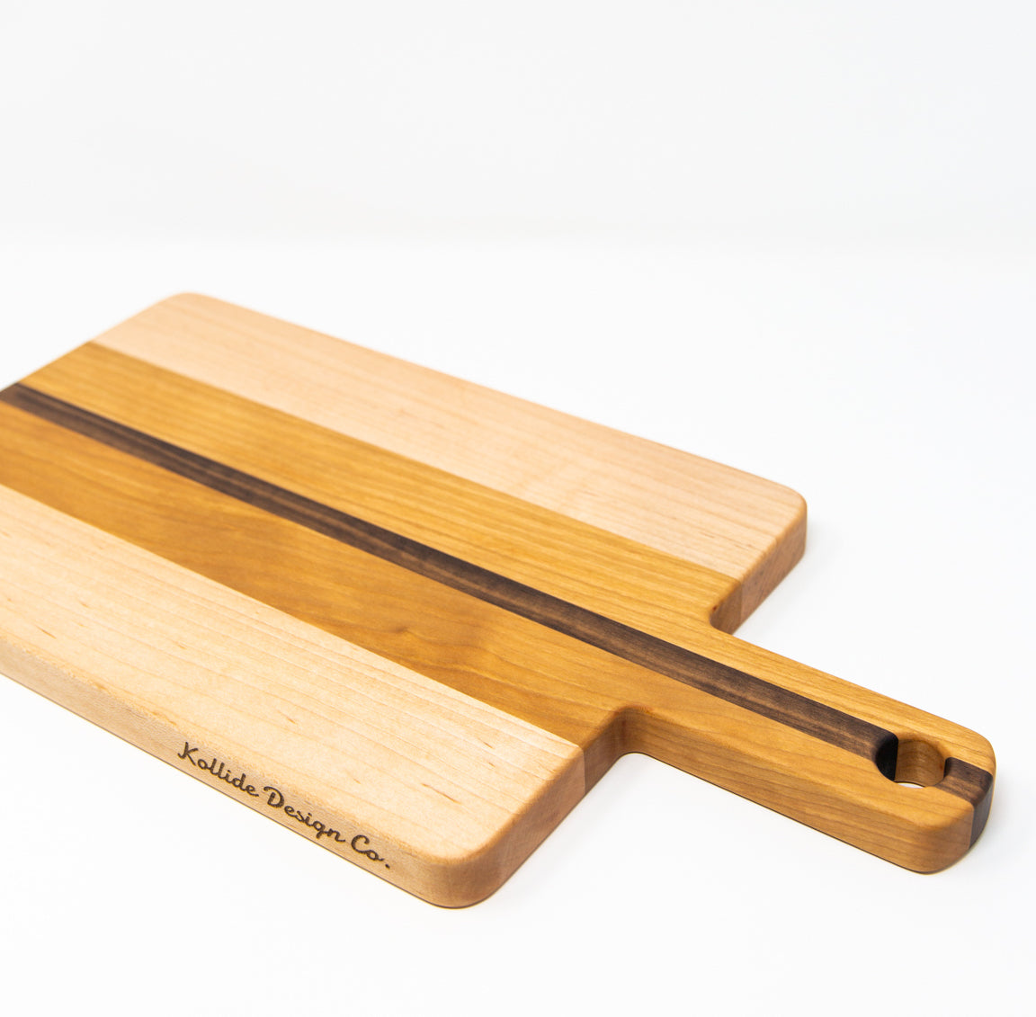 Small wood charcuterie board, made of light blonde Maple, golden-brown Cherry and a center strip of dark Walnut, with a timeless rectangular shape and a straight handle.