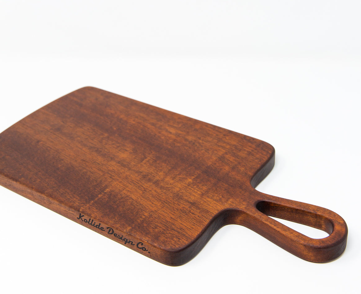 Extra small wood charcuterie board, made of a dark reddish-brown Sapele, with smooth curves and a unique teardrop handle.
