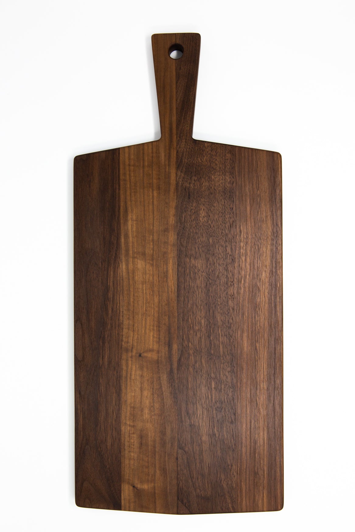 Large size wood charcuterie board, made of dark Walnut, with a slightly tapered handle and a long rectangular body.