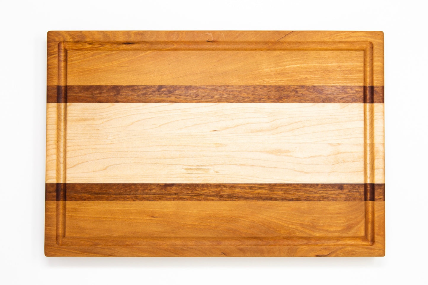 Large size wood cutting board, made of golden-brown Cherry, dark reddish-brown Sapele and light blonde Maple, with a juice groove and side handles.