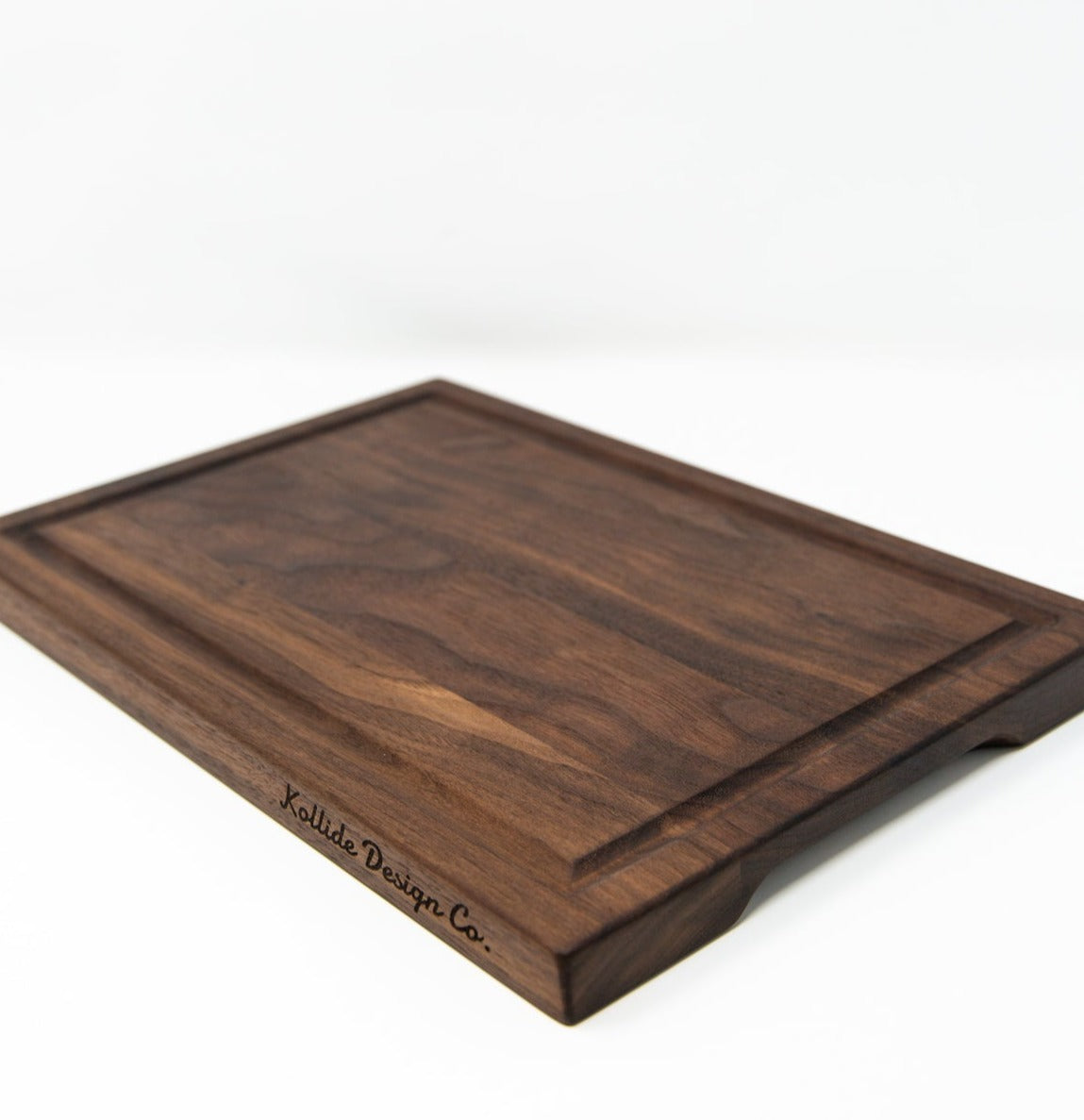 Small wood cutting board, made of dark Walnut, with a juice groove and side handles.